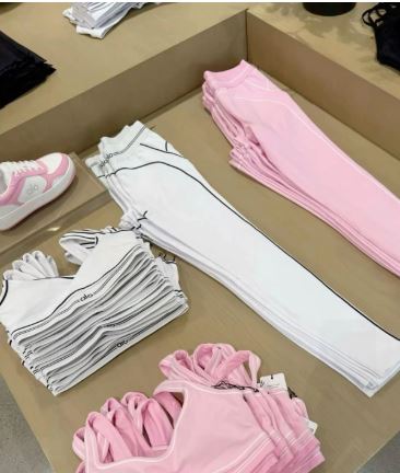 Folded pink athletic apparel stacked neatly on a clean white surface.