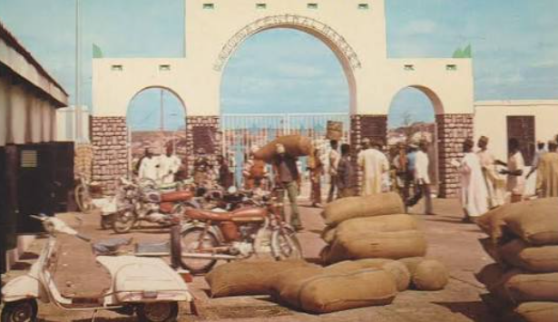 Rows of concrete market shops displaying colorful African wax print fabrics in Nigeria.
