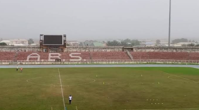 Concrete stadium canopy covering rows of sports spectator seating in a Nigerian venue.