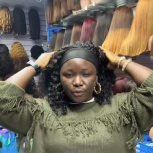 Students learning wig installation techniques inside a brightly lit local Nigerian beauty academy room.