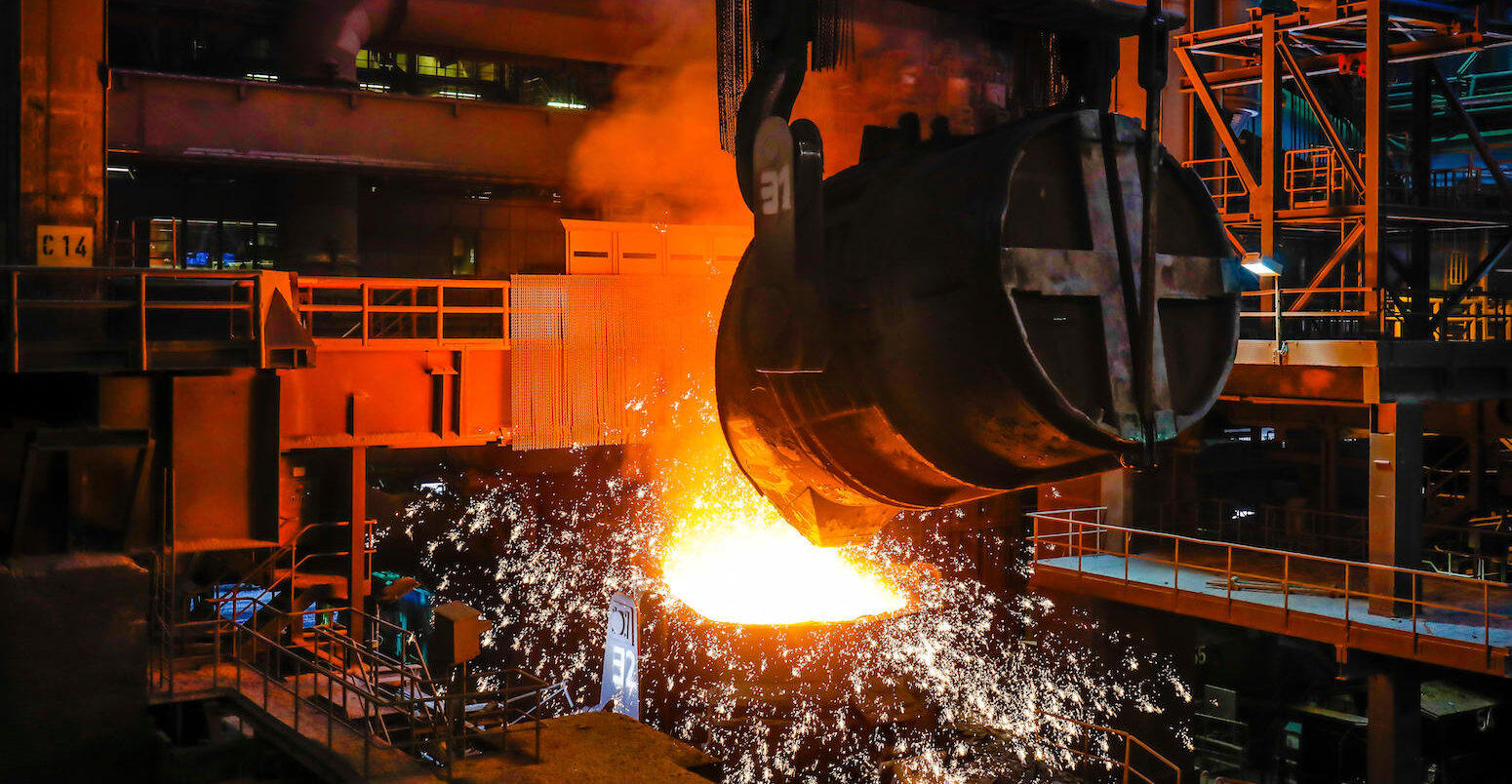Steel manufacturing plant interior showing heavy industrial operations.