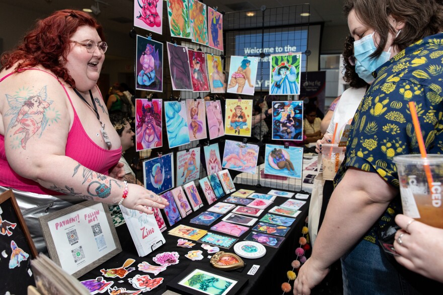 Artisans and designers interacting with attendees at a fashion marketplace.