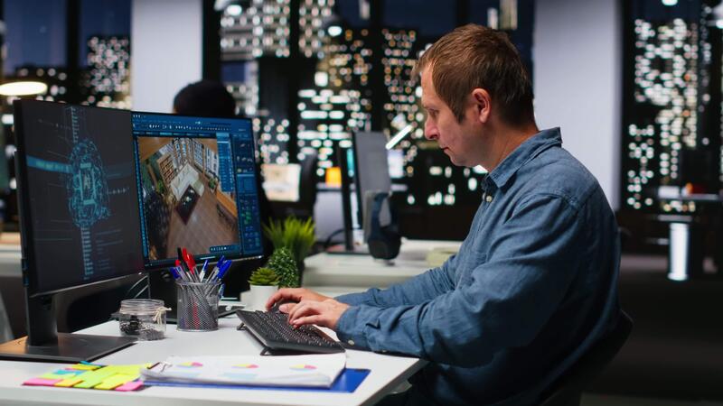 Software engineer working on 3D architectural design and floor plans in a modern office.