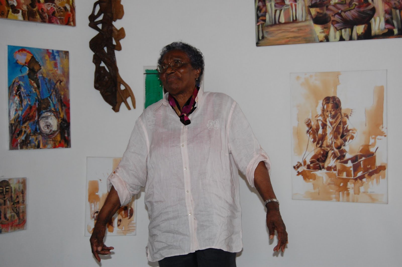 An artist standing among artwork displayed at an exhibition.