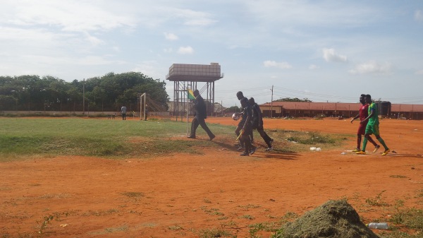 Local youth players practicing finishing drills on a community football pitch in Kumasi, Ghana.