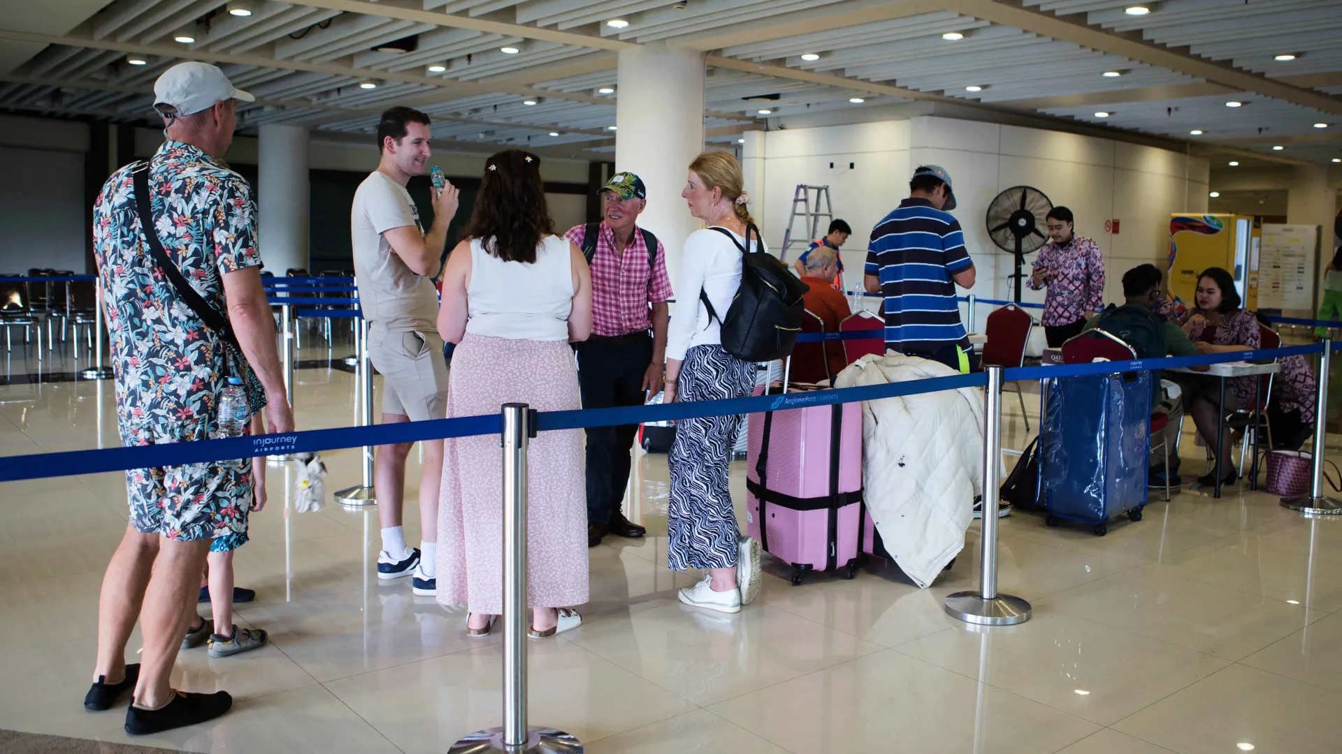 Travelers waiting inside the terminal at an airport.
