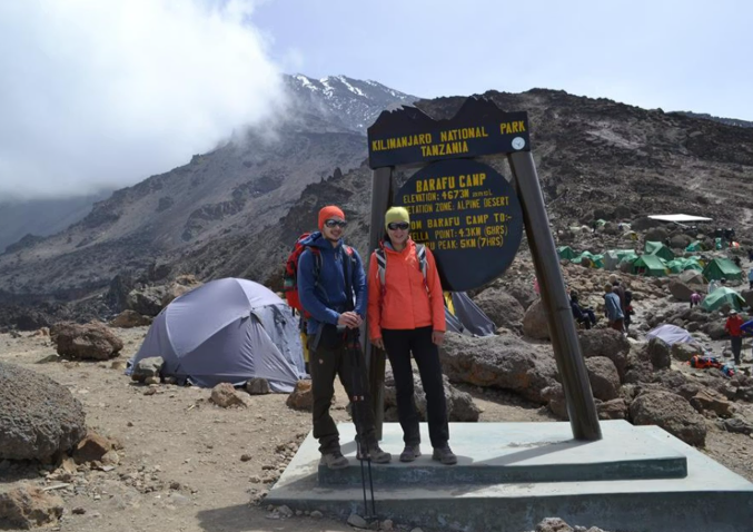 Climbers posing by the Barafu Camp sign at an elevation of 4,673m in the alpine desert zone of Mount Kilimanjaro in Tanzania.