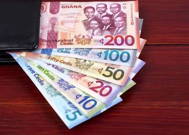 Close-up of Ghanaian cedi banknotes resting on a flat surface.