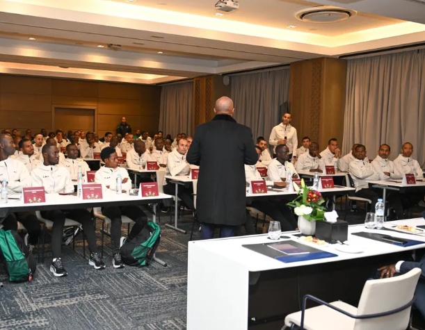 A speaker leading a workshop or presentation for sports delegates in a conference room.