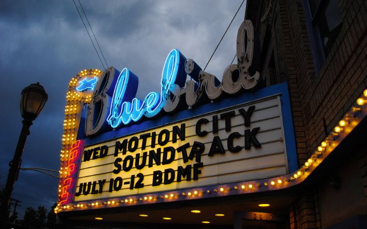Brightly lit cinema marquee against an evening sky.