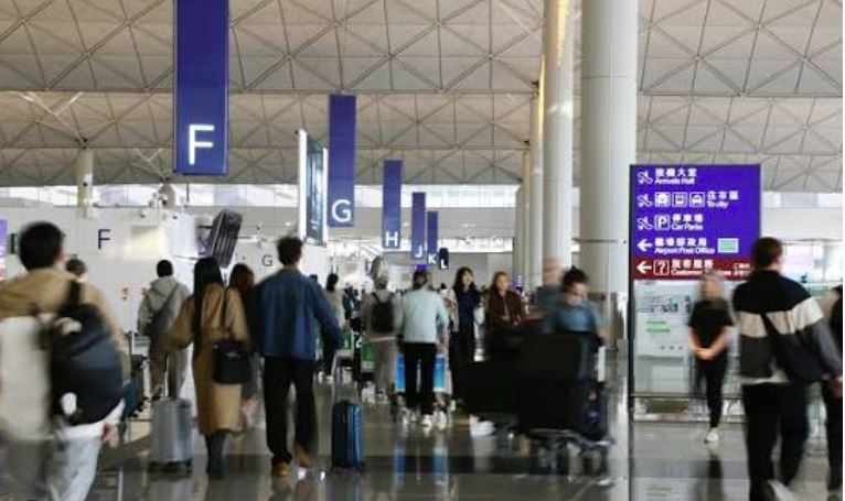 Bright airport terminal interior with travelers walking near gates.