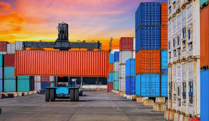 Busy international container terminal yard with stacked freight containers and heavy lifting equipment.