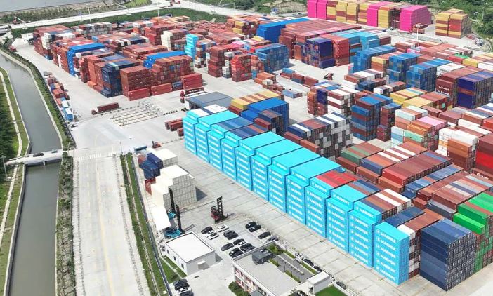 Cargo shipping containers stacked at a major industrial freight terminal.