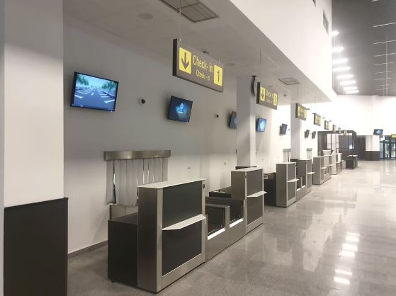 Busy airport check-in hall with passengers standing near ticket counters.