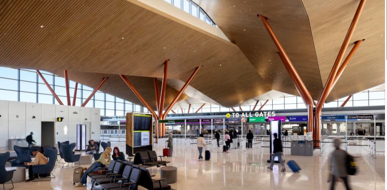 Busy airport departure terminal with passengers walking near boarding gates.
