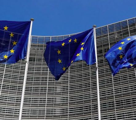 Modern European Union flag fluttering outside an administrative complex.