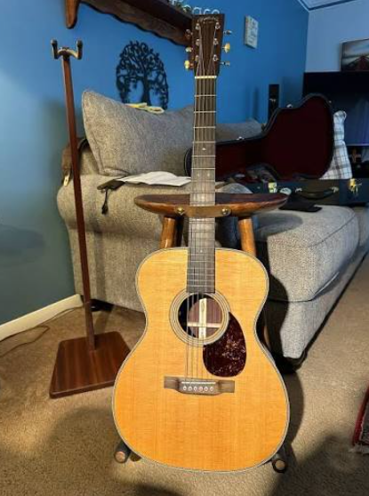 A vintage acoustic guitar resting on a wooden chair alongside sheet music.