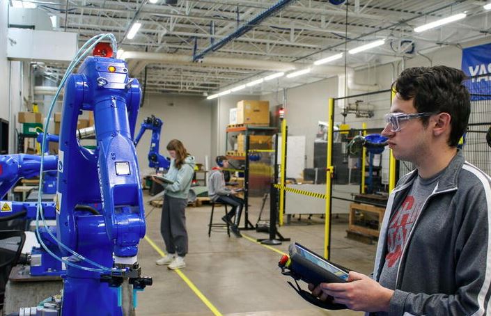 Engineers working with automated machinery inside a clean industrial laboratory.