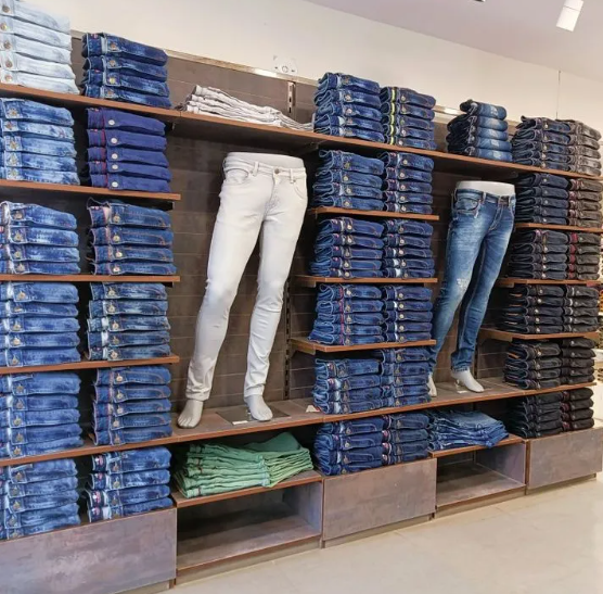 Denim garments neatly arranged on a retail display shelf.