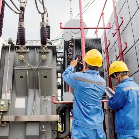 Engineers wearing hard hats working on power grid equipment.