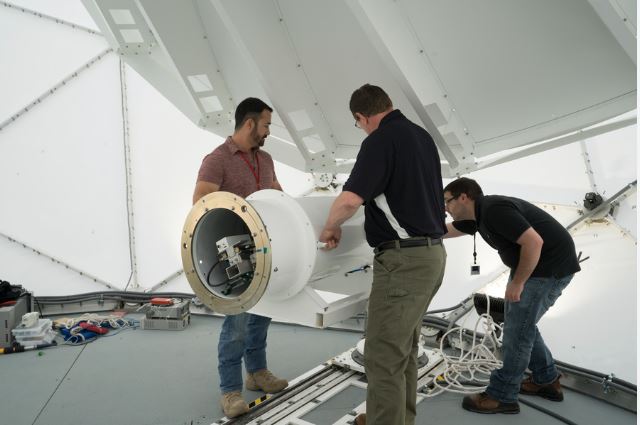 Close-up of high-tech optical satellite components on a cleanroom workbench.